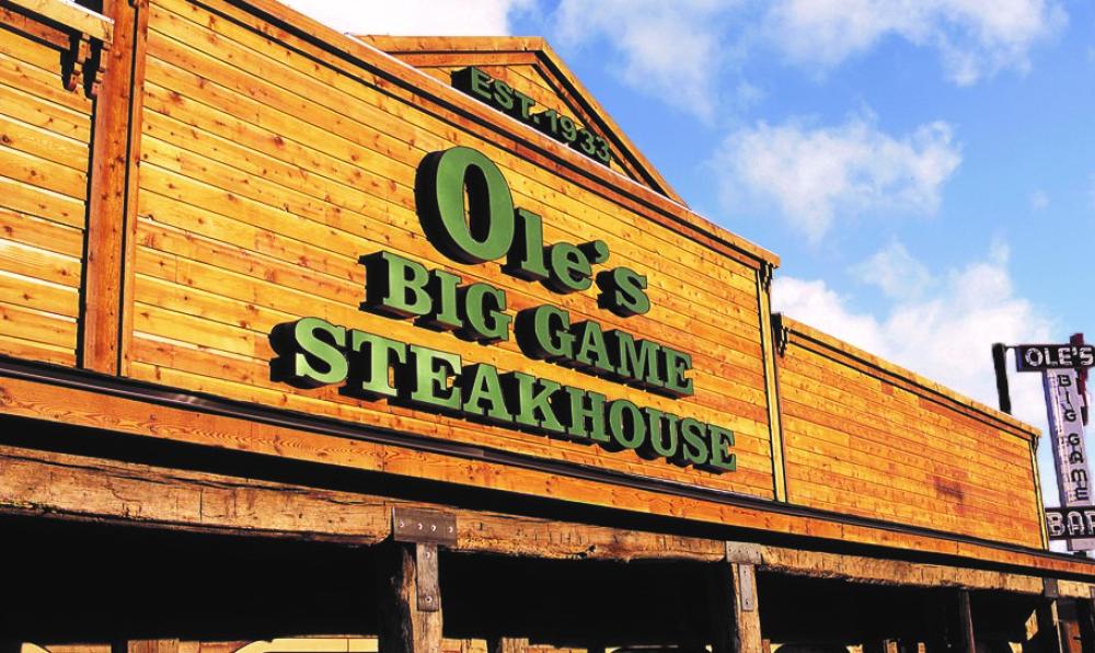 The wooden entrance and green Ole’s Big Game Steakhouse sign.