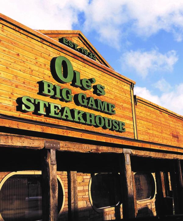 The wooden entrance and green Ole’s Big Game Steakhouse sign.